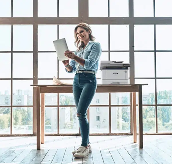 Xerox B305 monochrome printer next to a smiling woman in a professional environment, illustrating ease of use and print quality for professionals, available via D&O Partners.