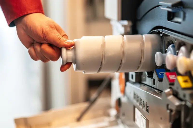 Hand of a technician holding a Xerox printer toner for replacement, in a very simple way, illustrating the reliable service and quality supplies of D&O Partners.