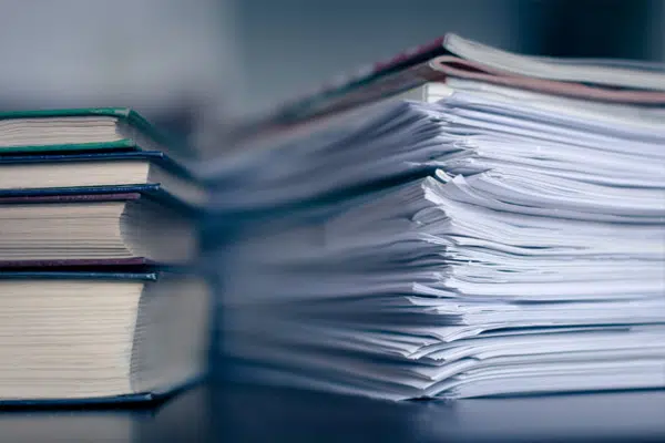 Pile de documents et livres illustrant la gestion documentaire par Xerox et D&O Partners.