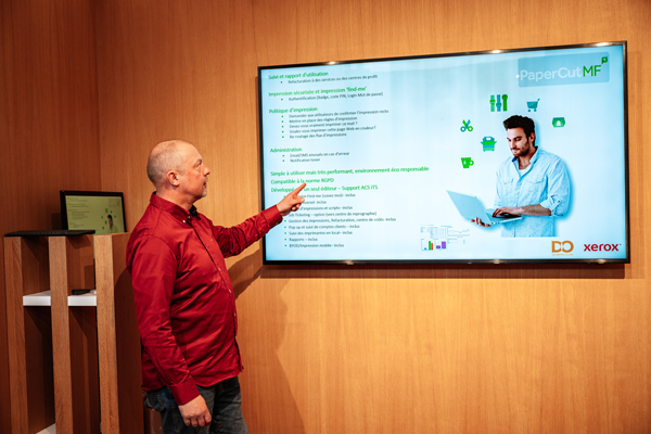 Notre spécialiste App's présentant un outil de stratégie de gestion de l'impression sur un grand écran, illustrant les services professionnels de D&O Partners.