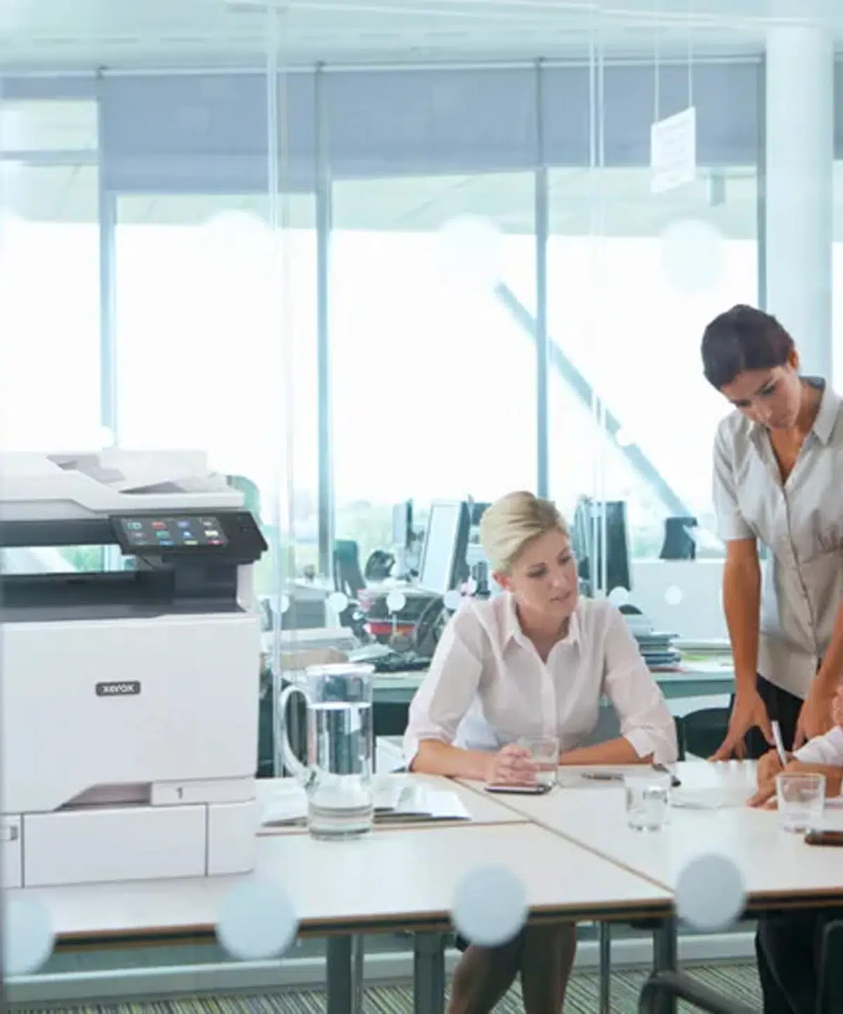 imprimante-couleur-versalink-c625-environnement-professionnel-xerox-belgique D&O Partners' Xerox VersaLink C625 printer installed next to two professionals talking in a bright, modern office, illustrating a collaborative working environment.