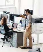 Employés de bureau travaillant à côté d’une imprimante multifonction Xerox VersaLink B625 dans un environnement de travail moderne.