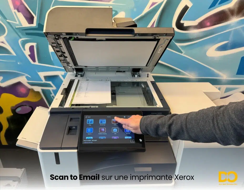 Utilisateur sélectionnant la fonction de numérisation vers e-mail sur l’écran tactile d’une imprimante multifonction Xerox avec le capot du scanner ouvert.