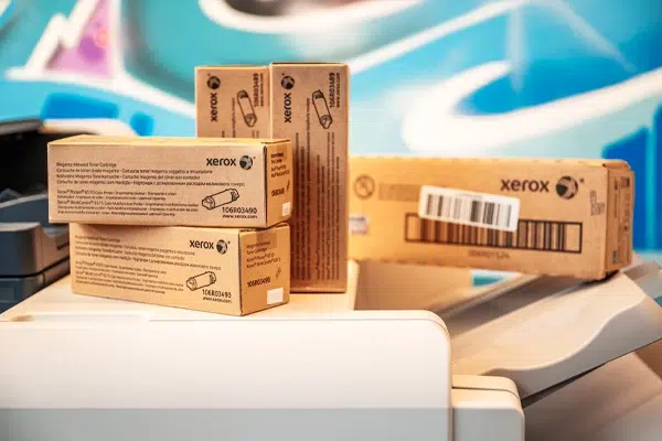 Cartouches de toner Xerox authentiques empilées sur un copieur, mettant en avant le service de livraison de consommables proposé par D&O Partners, soulignant la facilité et l'efficacité de la gestion des fournitures d'impression.