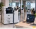 Xerox A3 multifunctionele printer in een kantooromgeving, verbonden met een Managed Print Services-dashboard voor centraal printerbeheer.